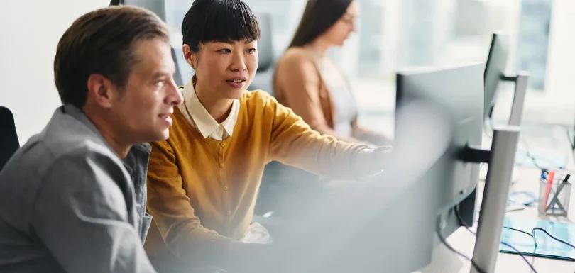 Two professionals looking at a set of computer screens.